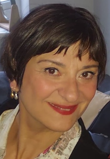 A headshot of Aylin, with short dark hair and small earrings, face turned slightly to the right.